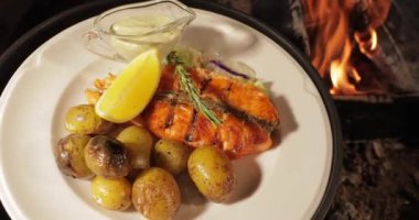 Izgara balık beyaz tabakta patates, limon ve sos, çıplak ateş, kırmızı kömür, duman, yakacak odun, 