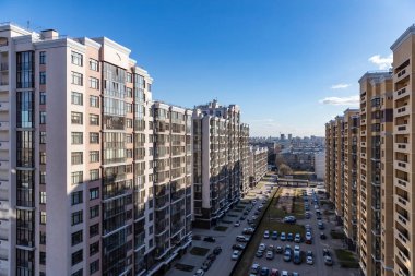 Balkondan rengarenk, çok katlı yeni binalar, yüksek katlı bir binanın ön cephesinin çok renkli tasarımının en üst görüntüsü. Apartman daireleri ve otoparklı bahçe.