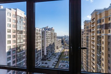 Balkondan rengarenk, çok katlı yeni binalar, yüksek katlı bir binanın ön cephesinin çok renkli tasarımının en üst görüntüsü. Apartman daireleri ve otoparklı bahçe.