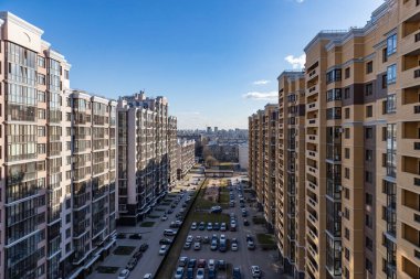 Balkondan rengarenk, çok katlı yeni binalar, yüksek katlı bir binanın ön cephesinin çok renkli tasarımının en üst görüntüsü. Apartman daireleri ve otoparklı bahçe.