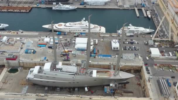 Vista aérea del muelle seco de mar en la ciudad de La Ciotat, Francia, la grúa de carga, barcos en reparación, un yate de vela de lujo y yate de motor, la montaña está en el fondo, astillero — Vídeo de stock