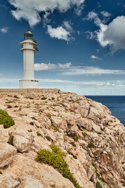 Farol na ilha Formentera, Espanha, o céu azul com nuvens brancas, sem pessoas, rochas, pedras, tempo ensolarado — Fotografia de Stock