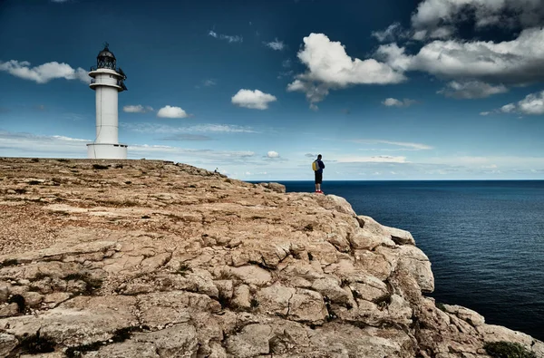 Leuchtturm auf der Insel Formentera, Spanien, blauer Himmel mit weißen Wolken, Person mit Tasche am Felsrand, Steine, sonniges Wetter — Stockfoto