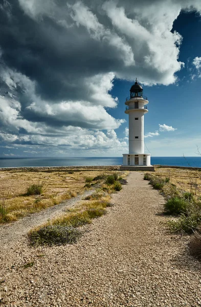 Farol na ilha Formentera, Espanha, o céu azul com nuvens brancas, sem pessoas, rochas, pedras, tempo ensolarado — Fotografia de Stock