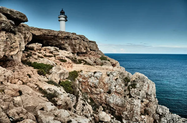 Farol na ilha Formentera, Espanha, o céu azul com nuvens brancas, sem pessoas, rochas, pedras, tempo ensolarado — Fotografia de Stock