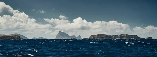 El Paisaje del mar baleárico y las montañas improbables, el agua azul, el cielo de tormenta, el barco solitario en el horizonte — Foto de Stock