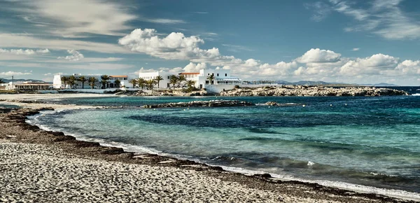 A paisagem do mar baleares e Baía de beleza improvável, água azul, céu com nuvens, edifícios solitários está no fundo, praia sem pessoas — Fotografia de Stock