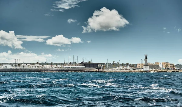 Spanien, Formentera, 29 april 2018: Den berömda hamnen i Formentera, en fyr, azurvatten, båtar, soligt väder, utan människor — Stockfoto