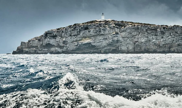 Farol está à beira da rocha, a paisagem do mar baleares e montanhas improváveis, água azul, o céu tempestade, montanhas — Fotografia de Stock