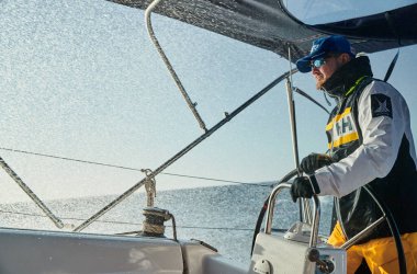 İspanya, Malorca, 29 Nisan 2018: Yat direksiyonundaki vahşi adam, fırtına sırasında yüzeye doğru uçuyor, aşırı eğlence, insan su geçirmez kıyafetler ve güneş gözlüğü takıyor., 