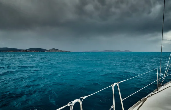 Вид на море і гори з вітрильника, край дошки човна, слінги і мотузки, бризки з-під човна, дощова погода, драматичне небо — стокове фото