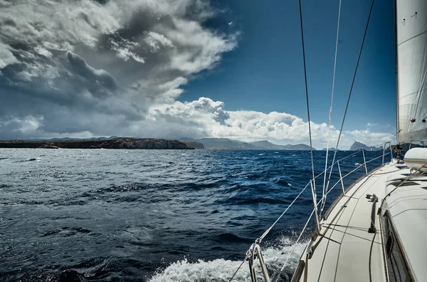 帆船からの海と山の景色、ボートのボードの端、スリングとロープ、ボートの下からのスプラッシュ、晴れた天気、劇的な空 — ストック写真