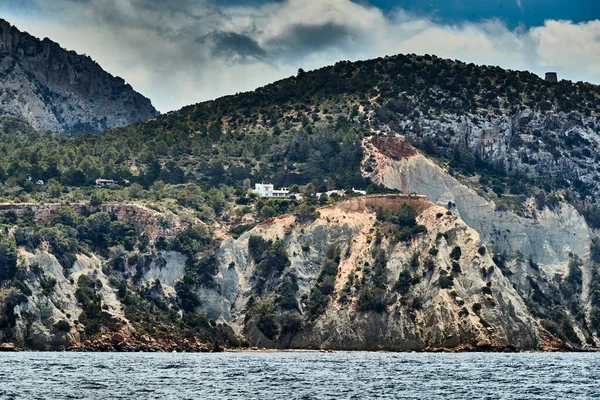 A paisagem do mar baleares e montanhas improváveis, água azul, o céu tempestade, edifícios solitários no topo das montanhas, barco à vela está no fundo — Fotografia de Stock