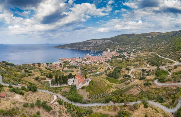 Vista panorámica aérea de la catedral de San Nicolás en la ciudad de Komiza - la de numerosas ciudades portuarias en Croacia, techos naranjas de casas, pintoresca bahía, montaña está en el fondo — Foto de Stock