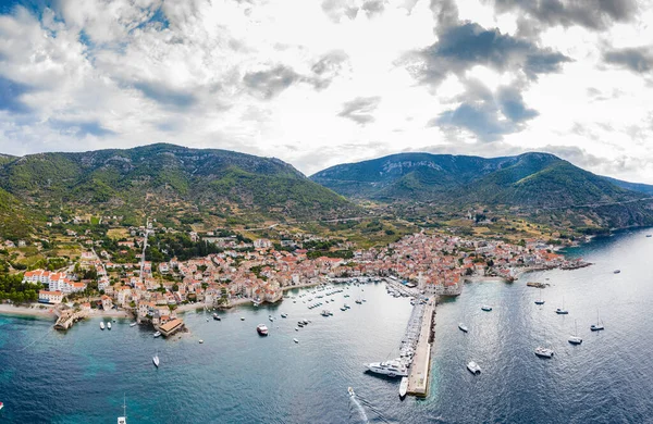 Hırvatistan 'ın sayısız liman kentinden biri olan Komiza kentinin havadan panoramik manzarası bir yelkenli yelkenlisi, turuncu evler, bir katedral St. Nicholas, Gusarica plajı., — Stok fotoğraf