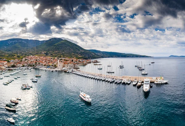 Vista panorâmica aérea da cidade Komiza - uma de cidades portuárias numerosas na Croácia, é muitos veleiros ancorados de uma regata, telhados cor-de-laranja de casas, uma catedral São Nicolau, praia Gusarica , — Fotografia de Stock