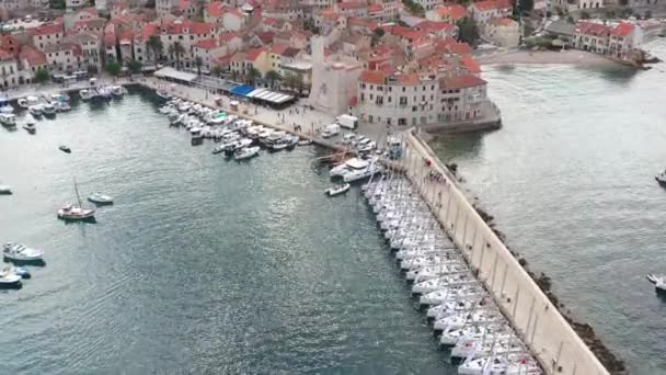 Luchtfoto panoramisch uitzicht op de stad Komiza - een van de vele havensteden in Kroatië, is veel afgemeerde zeilboten van een regatta, oranje daken van huizen, een kathedraal Sint Nicolaas, strand Gusarica, — Stockvideo