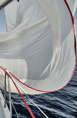 Beyaz renkte dönen yelkenli, rüzgarda dalgalanan yelkenli gün batımında yelken açan yelkenli yelkenli, bir yarış, suya yansıyan bir yansıma.