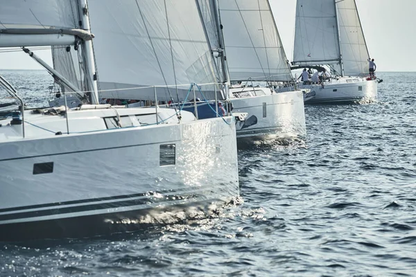 Segelbåtar tävla i en segling regatta vid solnedgången, segling ras, reflektion av segel på vatten, vit färg på segel, båtnummer akterbåtar — Stockfoto