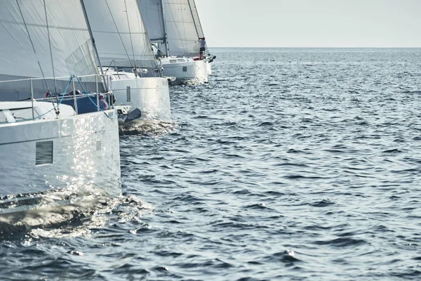 セーリングボートは、日没時のセーリングレガッタ、セーリングレース、水上の帆の反射、帆の白い色、ボートナンバーボートで競います — ストック写真