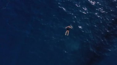 Hırvatistan, Adriyatik Denizi, 18 Eylül 2019: Kız mavi suda yüzüyor, gökyüzüne bakıyor, suda gün ışığı, suda güneşin yansıması