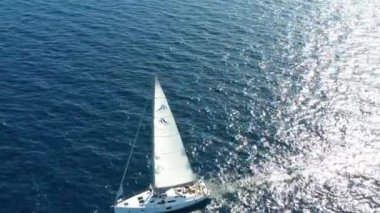 Birbirine yakın iki yelkenli yatı, gençlerin yatlarda eğlenmesi, gençlerin botların arasında asılı kalması, Adriyatik Denizi, Hırvatistan, arka planda adalar, suda güneş yansımaları, sükunet.