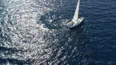 Birbirine yakın iki yelkenli yatı, gençlerin yatlarda eğlenmesi, gençlerin botların arasında asılı kalması, Adriyatik Denizi, Hırvatistan, arka planda adalar, suda güneş yansımaları, sükunet.