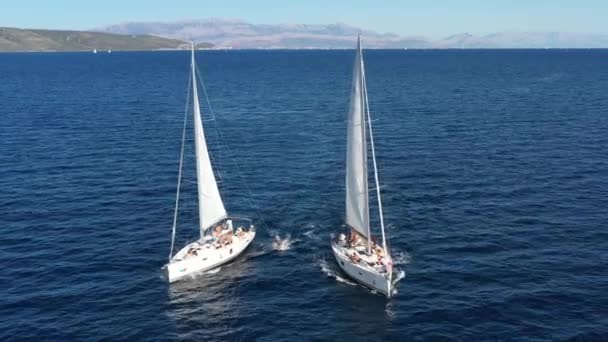 Два вітрильних яхти близько один до одного, молодь розважається на яхтах, молоді люди висять на мотузці між човнами, Адріатичне море, Хорватія, острови на задньому плані, сонячні роздуми на воді, спокій. — стокове відео