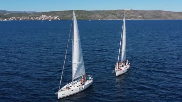 Zwei Segelyachten dicht beieinander, Jugendliche haben Spaß auf Yachten, junge Leute hängen an einem Seil zwischen Booten, die Adria, Kroatien, Inseln im Hintergrund, Sonnenreflexe auf dem Wasser, Ruhe — Stockvideo