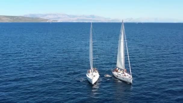 Due yacht a vela strettamente l'uno all'altro, i giovani si divertono sugli yacht, i giovani pendono su una corda tra barche, il mare Adriatico, Croazia, isole su uno sfondo, riflessioni solari sull'acqua, calma — Video Stock