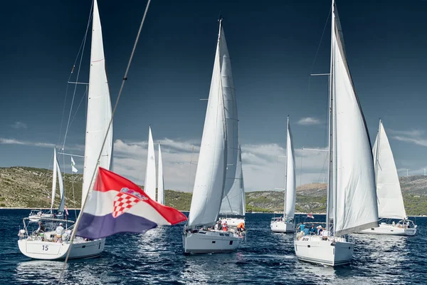 Segelboote konkurrieren bei Sonnenuntergang bei einer Segelregatta, Regatta der Segelboote, Reflexion der Segel auf dem Wasser, bunte Spinnaker, Anzahl der Boote auf Achterbooten, Helle Farben — Stockfoto