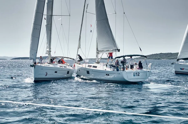 Croácia, Mar Mediterrâneo, 18 de setembro de 2019: Veleiros competem em regata de vela, a equipe desliga o barco, reflexo de velas na água, bandeira da Croácia, número de barcos está em barcos de popa — Fotografia de Stock