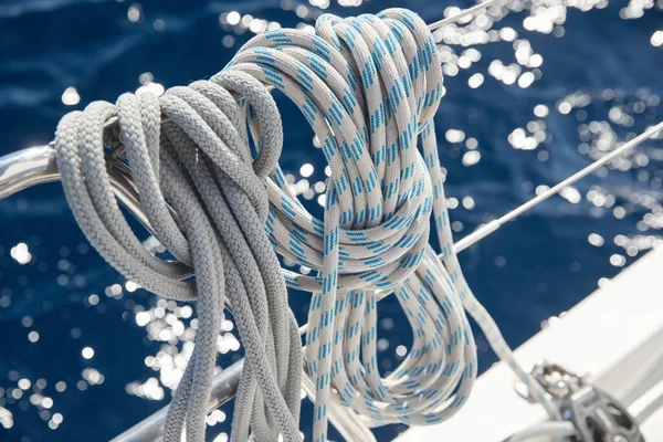 Close-up view of sailboat ropes at sunny weather, pulleys and ropes on the mast, Yachting sport, ship equipment, sea is on background Stock Picture