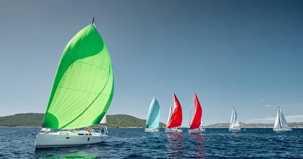 Veleiros competem em uma regata de vela ao pôr do sol, corrida de veleiros, reflexão de velas na água, spinnakers multicoloridos, número de barco está em barcos de popa, ilha está em segundo plano, tempo claro — Fotografia de Stock