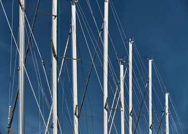 Arka planda mavi gökyüzü olan yelkenli direkleri, yelkenli yelkenli yelkenlisi, su, halat ve alüminyum direkleri, parlak renklerin yansıması