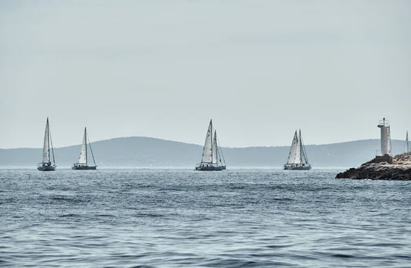 Schöne Meereslandschaft mit Segelbooten, das Rennen der Segelboote am Horizont, eine Regatta, ein intensiver Wettbewerb, leuchtende Farben, Insel mit Windmühlen im Hintergrund — Stockfoto
