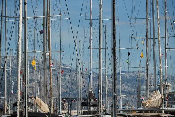 El número de mástiles de veleros con el cielo azul y las montañas sobre un fondo, una regata de vela, reflejo de mástiles en el agua, cuerdas y aluminio, colores brillantes — Foto de Stock