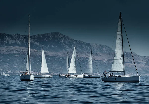 ヨットのレース、レガッタ、水上帆の反射、激しい競争、ボートの数はボートボートに乗っている、明るい色、風車のある島が背景にあります — ストック写真
