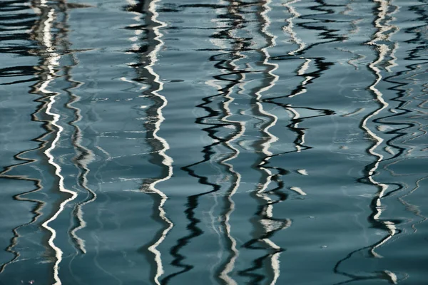 Reflexión de mástiles de veleros sobre agua, textura interesante, líneas suaves de agua, una regata de vela, reflejo de mástiles sobre agua, cuerdas y aluminio, colores brillantes — Foto de Stock