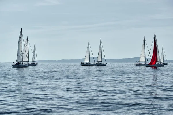 Croatia, Adriatic Sea, 15 September 2019: The race of sailboats, a regatta, reflection of sails on water, Intense competition, bright colors, island with windmills are on background — Stock Photo, Image