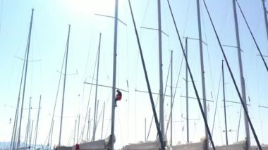 Hırvatistan, marina Kastela, 15 Eylül 2019: Denizcinin insansız hava aracı bakış açısı direğe asılı ve bayrakları bağlıyor, yelkenli yarışına katılan insanlar yaklaşan yarışı bekliyor