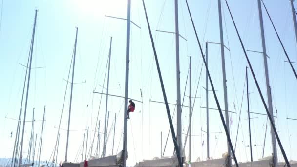 Hırvatistan, marina Kastela, 15 Eylül 2019: Denizcinin insansız hava aracı bakış açısı direğe asılı ve bayrakları bağlıyor, yelkenli yarışına katılan insanlar yaklaşan yarışı bekliyor — Stok video