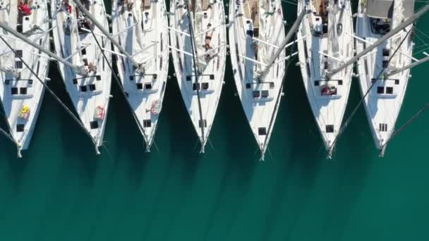 Horvátország, marina Kastela, 2019. szeptember 15.: Drone view point on moored in a equal row sailboat, participant of a sailing regatta, people 's waiting for the coming race, móló, close up — Stock videók