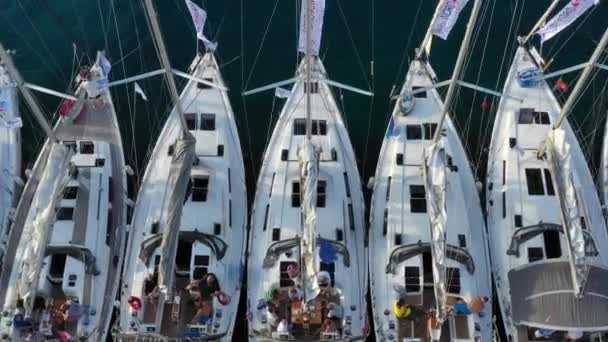 Croacia, Maslinica, 15 de septiembre de 2019: Punto de vista del dron amarrado en una fila igual veleros al atardecer, participante de una regata de vela, la gente descansa después del día de carreras, muelle, primer plano — Vídeo de stock