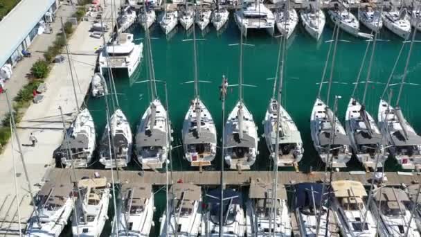 Croatia, marina Kastela, 15 September 2019: Drone view point of the sailor hangs in a cradle on a mast and binds flags, participant of a sailing regatta, people is waiting for the forthcoming race — Stock Video