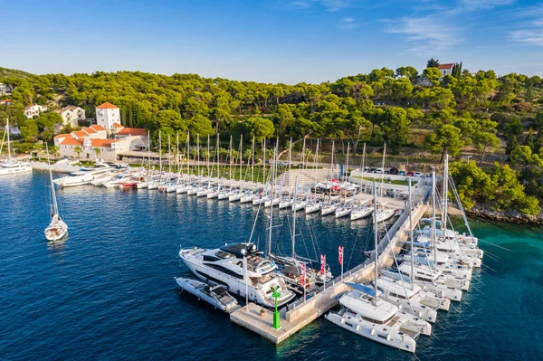 Croazia, Maslinica, 15 settembre 2019: Punto di vista drone su ormeggiato in una barca a vela di uguale fila al tramonto, partecipante a una regata di vela, le persone hanno un riposo dopo la giornata di regate, acqua azzurra, molo — Foto Stock