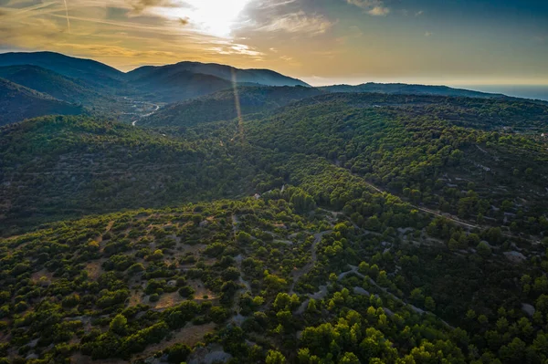Vista aérea de colinas com árvores verdes ao pôr do sol, Vis, Croácia, estrada entre montanhas — Fotografia de Stock