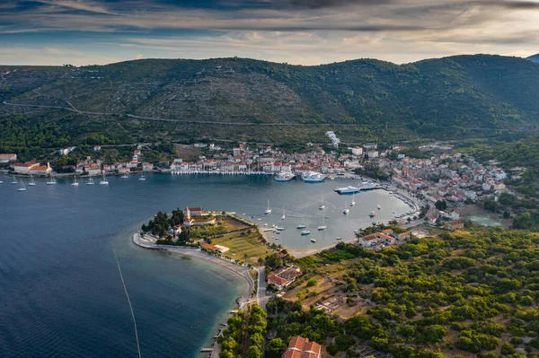 Aerial view of marina Vis at sunset, Croatia, a lot of chaotically standing boats in a bay, roofs of orange color, sunshine, hills with green trees, ferry station — Stock Photo, Image