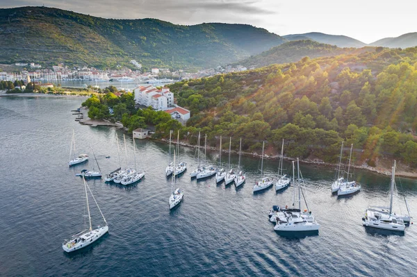 Vista aérea da marina Vis ao pôr-do-sol, Croácia, um monte de barcos de pé caoticamente em uma baía, telhados de cor laranja, sol, colinas com árvores verdes, estação de balsa — Fotografia de Stock