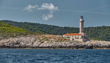 Hırvatistan 'ın yakınlarındaki Vis adasındaki deniz feneri, kayalık bir sahil, fenere giden bir merdiven, küçük bir pelerin.